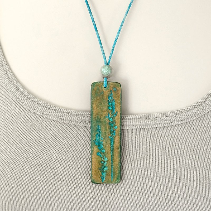 Nature-inspired leather pendant with hand-tooled grasses motive